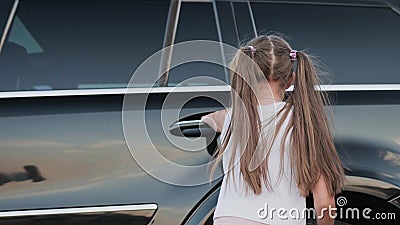 Little girl opening car door to getting in. Slow motion Stock Photo