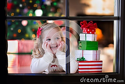 Little girl opening Christmas presents at fire place Stock Photo