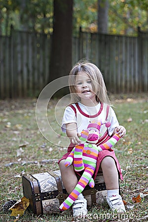 Little girl outdoors with toy monkey Stock Photo