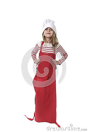 Little girl in oversized cooking hat and red apron playing cook smiling happy and playful Stock Photo