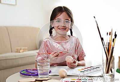 Little girl painting decorative egg at table. Creative hobby Stock Photo