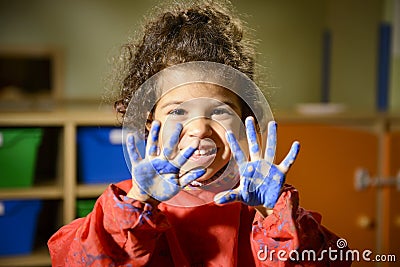 Little girl painting with hands in kindergarten Stock Photo