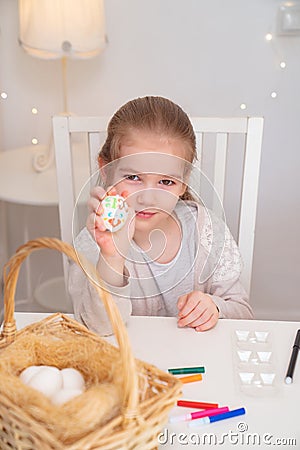 Girl paints eggs edible markers. Easter traditions Stock Photo