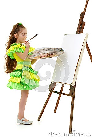 Little girl with a palette and brush near the easel. Stock Photo
