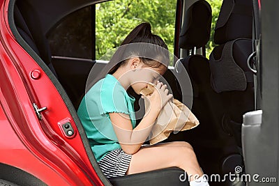 Little girl with paper bag suffering from nausea in car Stock Photo