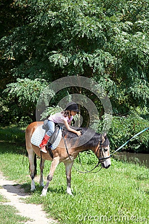 Little girl petting a horse while horseback riding Stock Photo