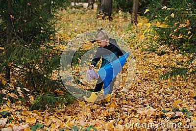 Little girl picking up piece trash in a seasonal forest at autumn Stock Photo