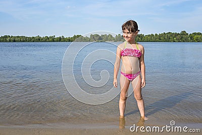 Little girl in a pink bathing suit on the river, on a sunny, warm day Stock Photo