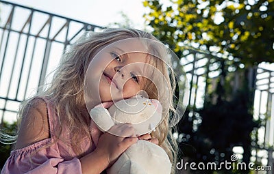 Little girl in a pink dress with a soft rabbit toy Stock Photo