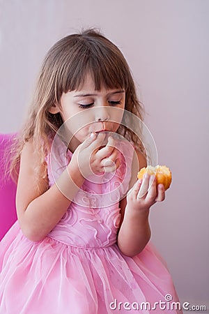 Little girl in pink fancy dress, eating sweet cupcake Stock Photo