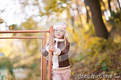 Funny portrait of a little girl. Little girl in a pink hat on a walk in the fall. Child girl in a jacket happily runs and collects Stock Photo