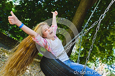 Little girl at playground. Child playing outdoors in summer. Teenager on a swing. Stock Photo