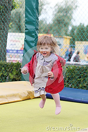 Little girl on playground in a park, jumping on trampoline Little Girl on a Trampoline Stock Photo