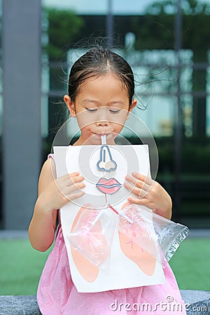 Little girl playing blowing with Simulate breathing of the lungs. Healthcare concept Stock Photo