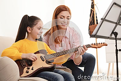 Little girl playing guitar with her teacher at music lesson Stock Photo