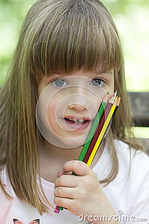 Little girl playing outside and holding crayons in hand Stock Photo