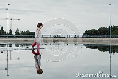 Little girl playing in a puddle, happy. stock photo Stock Photo