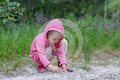 Little girl playing with sand in summer forest Stock Photo