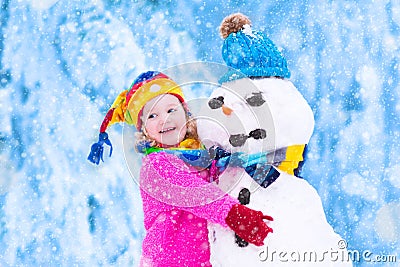 Little girl playing with a snowman Stock Photo