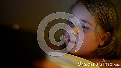 little girl is playing video games in tablet at night, internet addiction and insomnia of children Stock Photo