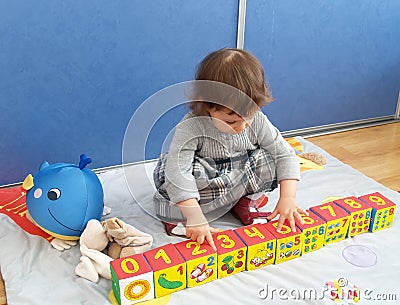 The little girl plays with cubes, sitting on a floor Stock Photo