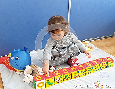 The little girl plays with cubes, sitting on a floor Stock Photo