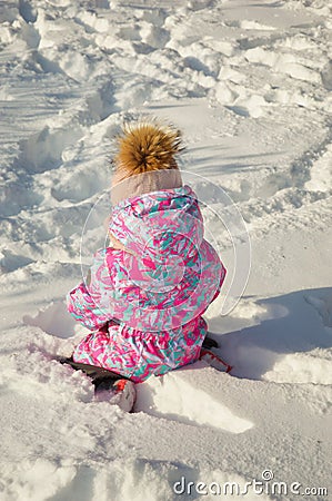 A little girl plays in the snow with snowballs in winter. Happy childhood. a child in a winter jacket. Stock Photo