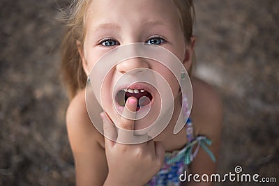 Little girl points the finger at a wobbly baby tooth Stock Photo