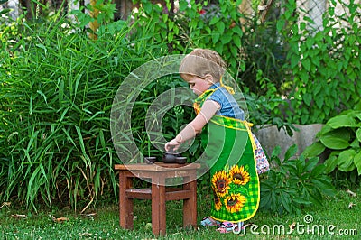 Little girl prepares Chinese tea in the yard of house. Stock Photo