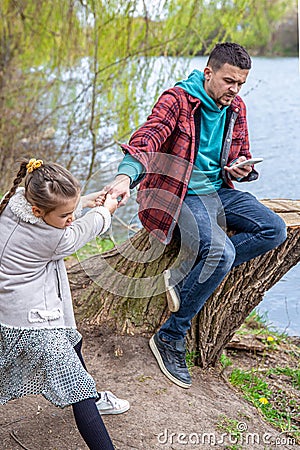 The little girl wants to go out with her dad, but he is busy with the phone Stock Photo