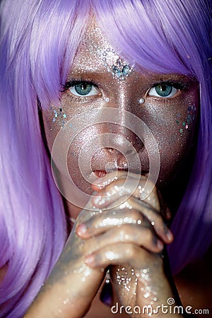 A little girl in a purple wig with silver sequins on her face. An alien, fantasy world.A fairy or an alien. Stock Photo