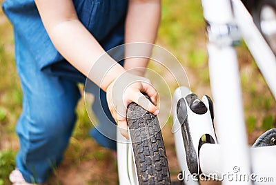 The little girl pushes the stroller with both hands and holds the rubber wheel outside during the day while walking. child`s hand. Stock Photo