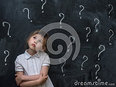 Little girl with question marks on blackboard. Concept for confusion, brainstorming and choice. Stock Photo