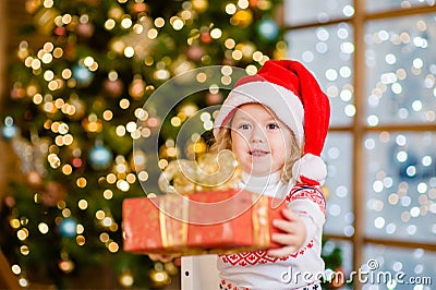 Little girl in a red Christmas hat gives a gift Stock Photo