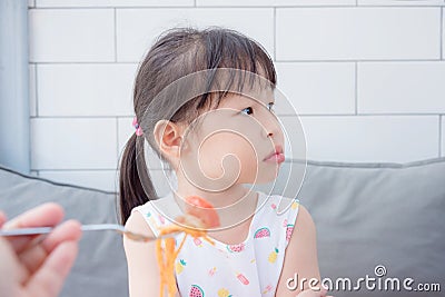 Little girl refuse to eat tomato in spagethi from her mother Stock Photo