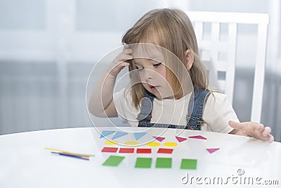 A little girl remembers geometric shapes. Early education Stock Photo