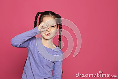 Little girl rubbing eye on color background, space for text. Stock Photo