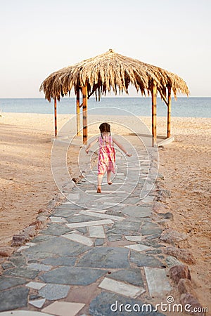 Little girl running to the sea. Rear view. Stock Photo