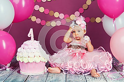 The little girl`s birthday girl was smeared into a cake. The first cake. The use of the first cake. Smash cake. Stock Photo