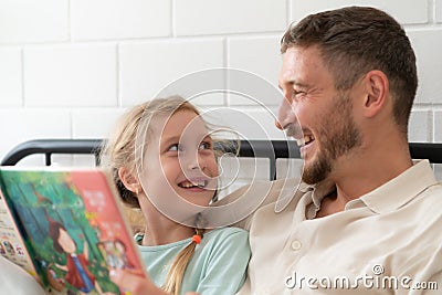 Little girl's father read stories to children before going to bed to unwind and sleep soundly Stock Photo