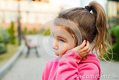 A little girl with a sad and frightened face holds her cheek with her hand - a tooth hurts. Ear pain, toothache, swollen cheek and Stock Photo