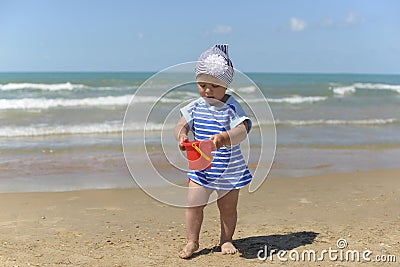 A little girl in a scarf playing on the sandy beach Stock Photo