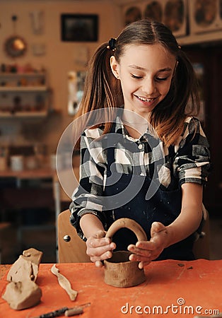 A little girl sculpts a basket of clay Stock Photo