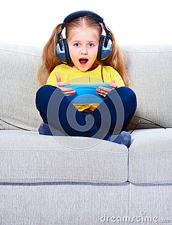 Little girl seating on sofa using tablet pc. Stock Photo
