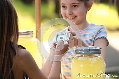 Little girl selling natural lemonade to kid in park Stock Photo