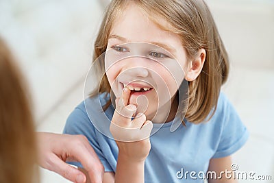 Little girl shows mother reeling tooth. changing milk teeth to indigenous teeth. Stock Photo