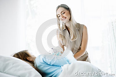 The little girl sick lying in bed at hospital and mother`s giving teddy bear to her daughter. Medical palliation healthcare Stock Photo