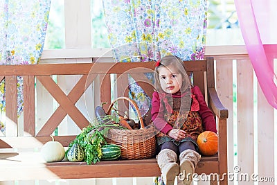 Little girl sits on a bench on a terrace Stock Photo