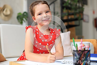 Little girl sits at the desl at home and does homework, self study of the material, reading book Stock Photo