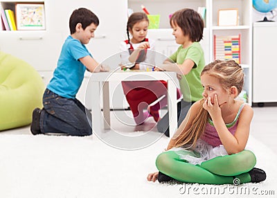 Little girl sitting apart - feeling excluded by the others Stock Photo
